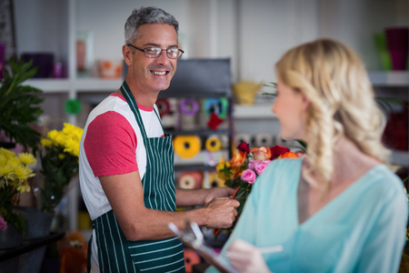 Smiling florists interacting with each other at flower shopの写真素材