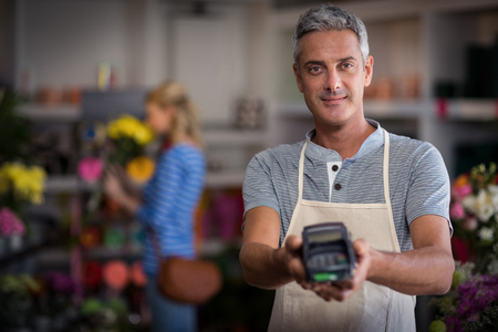 Portrait of florist showing credit card terminal in flower shopの写真素材