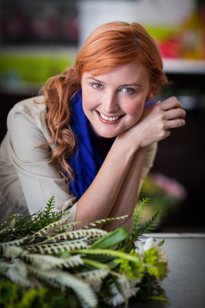 Portrait of happy female florist leaning in flower shopの写真素材