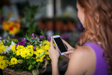 Female florist taking photogrpah of flower basket in the flower shopの写真素材
