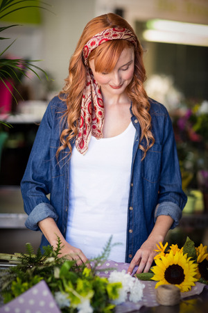 Female florist wrapping flower bouquet in flower shopの写真素材