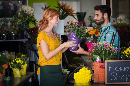 Female florist giving flower bouquet to man in the flower shopの写真素材