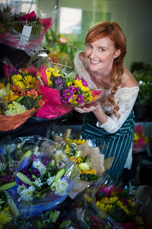 Female florist touching flower bouquet in the flower shopの写真素材