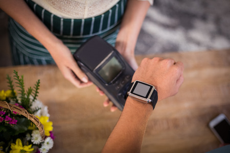 Hand of customer making payment through smartwatch in the flower shopの写真素材