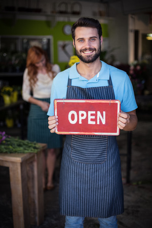 Male florist holding open signboard in the flower shopの写真素材