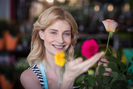 Portrait of smiling female florist arranging flower bouquet in vase at flower shopの写真素材