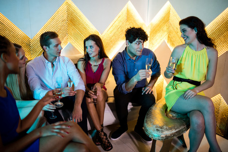 Group of smiling friends interacting while having a glass of champagne at barの写真素材