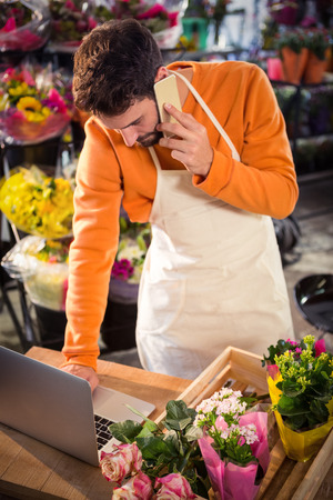 Male florist taking order on laptop at his flower shopの写真素材