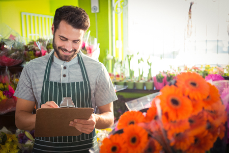 Male florist writing and making notes at his flower shopの写真素材