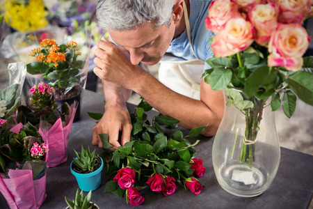 Male florist arranging flowers at his flower shopの写真素材