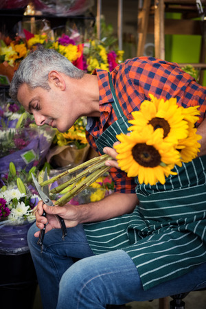 Male florist trimming stems of flowers at his flower shopの写真素材