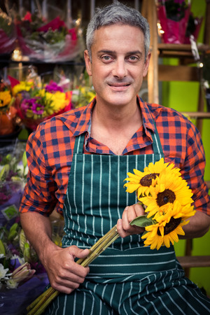 Portrait of male florist holding bunch of flowers at his flower shopの写真素材