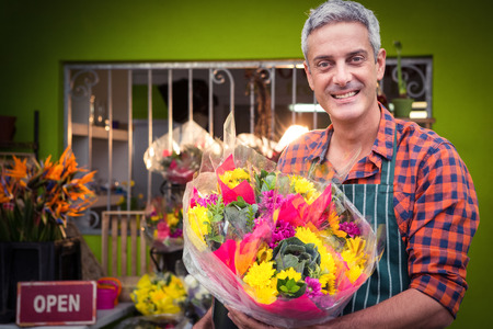 Portrait of male florist holding flower bouquet at his flower shopの写真素材