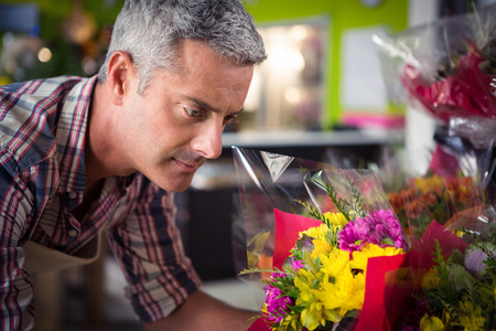 Close-up of male florist arranging bouquet of flower at his flower shopの写真素材