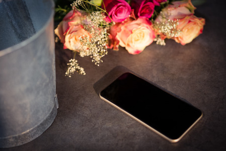 Close-up of pink roses and smartphone on the tableの写真素材