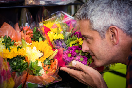 Close-up of male florist smelling flower at his flower shopの写真素材