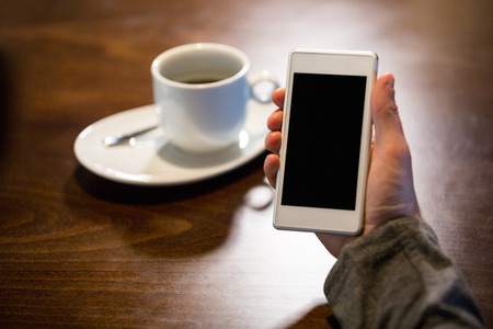 Close-up of man holding mobile phone in restaurantの写真素材