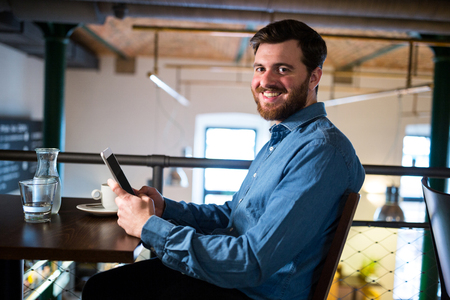Portrait of man text messaging on mobile phone in restaurantの写真素材