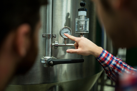 Maintenance workers examining pressure at brewery factoryの写真素材