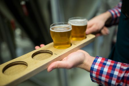 Close-up of brewer holding beer sampler tray at brewery factoryの写真素材