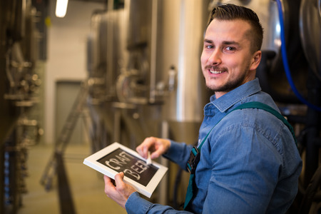 Portrait of happy brewer writing on slate at breweryの写真素材