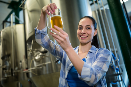 Portrait of happy female brewer testing beer at brewery