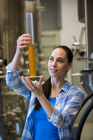 Beautiful female brewer hydrometer cylinder at brewery factoryの写真素材