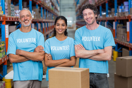 Happy volunteer are posing with crossed arms in a warehouseの写真素材