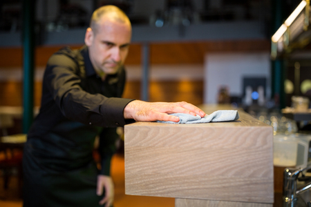 Close-up of bar tender cleaning bar counter at bar