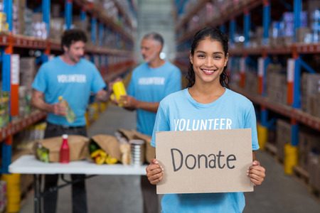 Portrait of happy volunteer holding a sign in a warehouseの写真素材