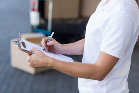 Close up of delivery woman is writing on a clipboard next to her vanの写真素材