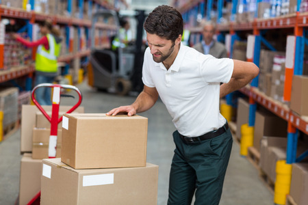 Focus of worker having a backache in a warehouseの写真素材