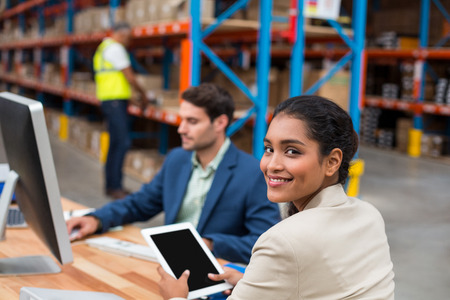 Rear view of managers are working on a desk in a warehouseの写真素材