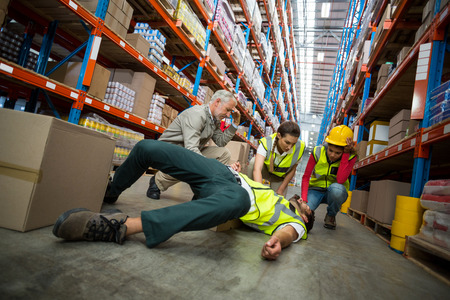Workers taking care about their colleague lying on the floor in a warehouseの写真素材