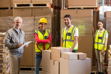 Manager and workers are smiling and posing in a warehouseの写真素材