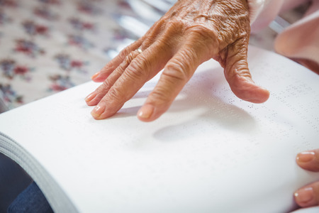 Senior woman using braille to read in a retirement homeの写真素材