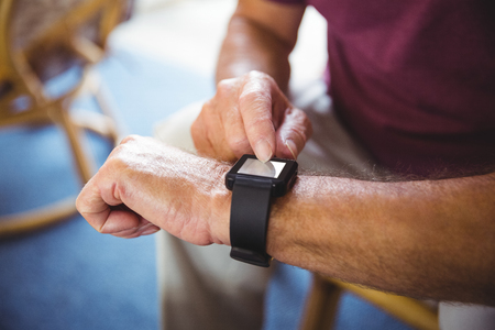 Senior man using a smart watch in a retirement homeの写真素材