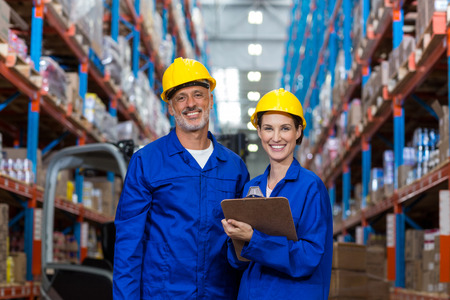 Coworkers looking at camera in warehouse