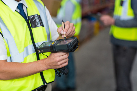 Close-up of worker touching digital equipment in warehouseの写真素材