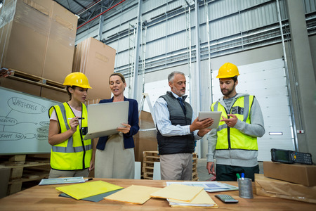 Warehouse team working on laptop and digital tablet in warehouse