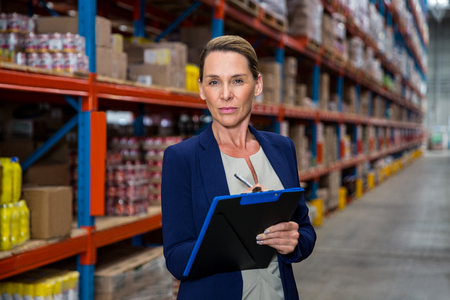 Business woman posing with her clipboard in a warehouseの写真素材