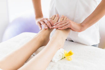 Midsection of masseur giving foot massage to woman at spaの写真素材