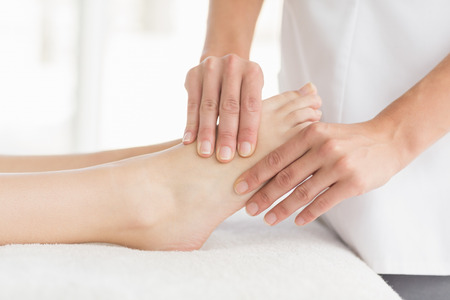 Midsection of masseur giving foot massage to woman at spaの写真素材