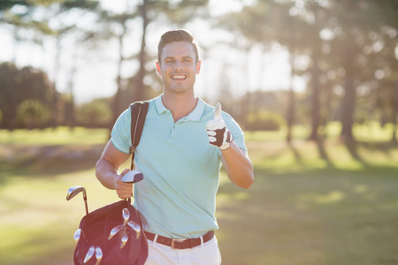 Portrait of smiling golfer man showing thumbs up  while standing on fieldの写真素材