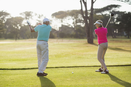 Full length of male golf player teaching woman while standing on fieldの写真素材