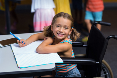 Little girl in wheelchair in classroom at schoolの写真素材