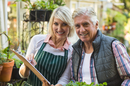 Portrait of confident male and female gardeners outside greenhouseの写真素材