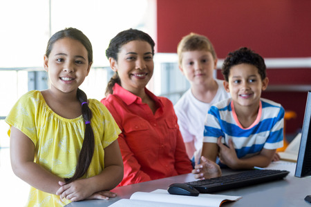 Smiling female teacher with children in computer room