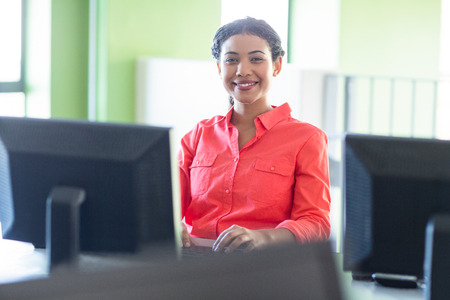 Portrait of smiling female teacher using computer in classroom