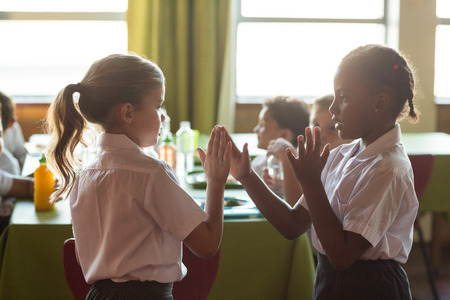 Schoolgirls playing clapping game in canteen